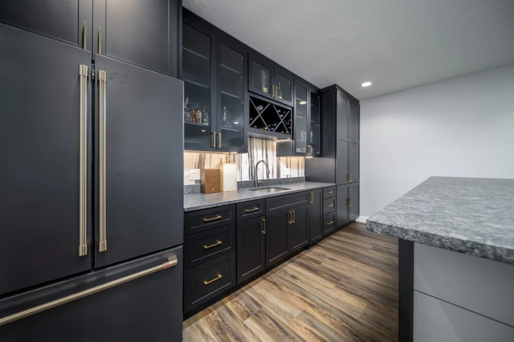 Modern kitchen with black cabinets, brass handles, marble countertops, under-cabinet lighting, wood-style flooring, and a built-in wine rack for custom comfort beyond builder grade finishes.