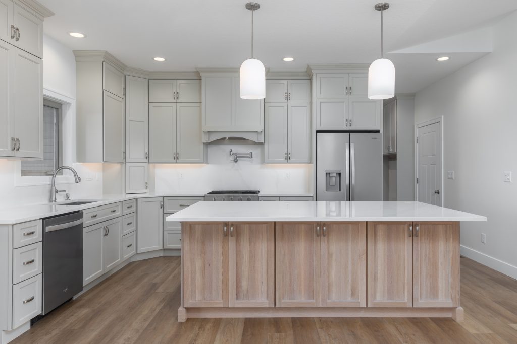 Bright modern kitchen with white cabinets, stainless-steel appliances, and a wooden island in the foreground.