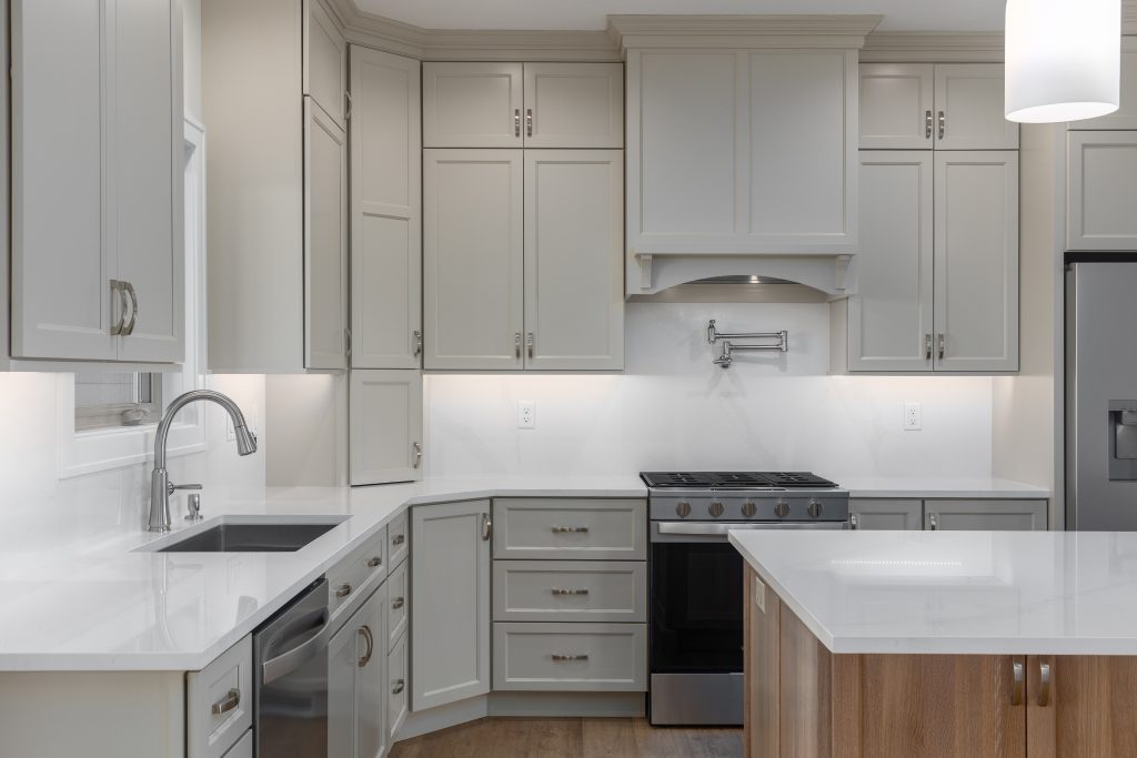 Modern gray kitchen with white marble countertops, stainless steel appliances, and an island with wood base.